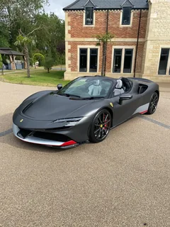 Matte grey Ferrari SF90 Spider parked on a gravel drive